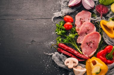 Taze sebze ve biberiye ve baharat siyah ahşap zemin sığır eti biftek. Üstten Görünüm. Metin için boş alan.