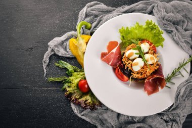 Jambon, bıldırcın yumurtası, Kuru erik ve plaka üzerinde taze sebze salatası. Ahşap bir arka plan üzerinde. Üstten Görünüm. Metin için boş alan.