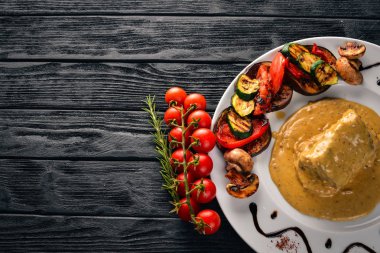 Eti biftek sosu ve ızgara sebzeler. Biftek Voronov. Ahşap bir arka plan üzerinde. Metniniz için boş alan. Üstten Görünüm.