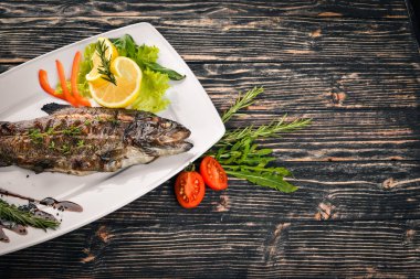 Balık alabalık pişmiş sebze ve baharatlar ile. Ahşap bir arka plan üzerinde. Üstten Görünüm. Metin için boş alan.