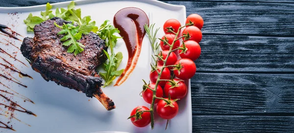 Steak on a bone with tomatoes and a hazelnut. Steak Fiorentino. On a wooden background. Free space for your text. Top view.