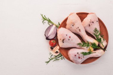 Biberiye ve baharat beyaz ahşap zemin üzerinde çiğ tavuk budu. Üstten Görünüm. Metin için boş alan