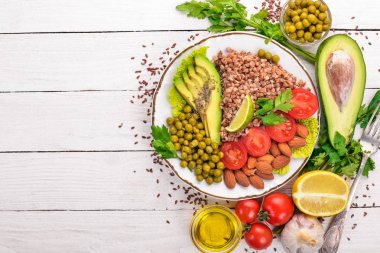 Sağlıklı gıda. Karabuğday, cherry domates, avokado, badem ve yeşil bezelye. Ahşap bir arka plan üzerinde. Üstten Görünüm. Metniniz için boş alan.