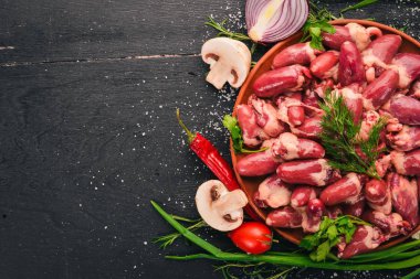 Çiğ tavuk kupa rosemary ile yemek pişirmek için hazır plaka üzerinde ve üzerinde baharat siyah ahşap arka plan. Üstten Görünüm. Metin için boş alan.