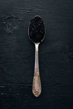Ahşap arka plan üzerinde siyah havyar kaşıkla. Üstten Görünüm. Metin için boş alan.