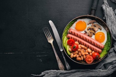 İngiliz kahvaltısı. Kızarmış yumurta, sosis, pastırma, fasulye, tost, domates, kahve fincanı taştan masada. Metin alanı olan Üstten Görünüm