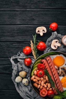 Tam İngiliz kahvaltısı kızarmış yumurta, sosis, fasulye, tost ve kahve kopya alan arka plan üzerinde. Siyah bir ahşap arka plan üzerinde.