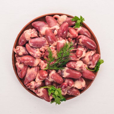 Raw chicken hearts on the plate ready for cooking with rosemary and spices on a white wooden background. Top view. Free space for text. clipart
