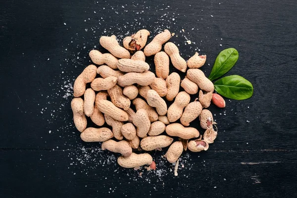 Peanuts on a dark wooden background. Healthy snacks. Top view. Free space for text.