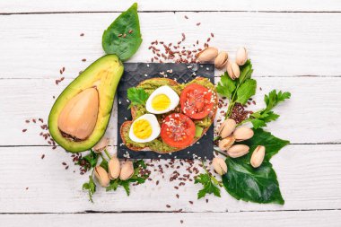 Bıldırcın yumurtası, avokado, domates ve antep fıstığı ile sandviç. Ahşap bir arka plan üzerinde. Üstten Görünüm. Metniniz için boş alan.