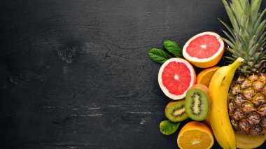 Taze tropikal meyve. Ananas, Hindistan cevizi, kivi, portakal, nar, greyfurt. Ahşap bir arka plan üzerinde. Üstten Görünüm. Metin için boş alan.