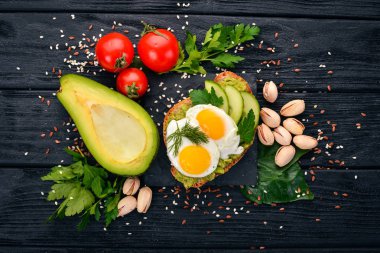 Bıldırcın yumurta, salatalık ve antep fıstığı ile avokado sandviç. Ahşap bir arka plan üzerinde. Üstten Görünüm. Metniniz için boş alan.