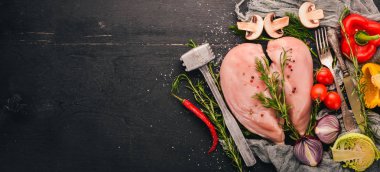 Taze sebze ve biberiye ve baharat siyah ahşap zemin ile çiğ tavuk göğsü fileto. Üstten Görünüm. Metin için boş alan.