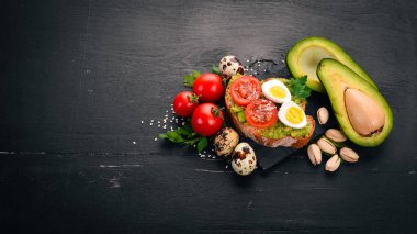 Bıldırcın yumurtası, avokado, domates ve antep fıstığı ile sandviç. Ahşap bir arka plan üzerinde. Üstten Görünüm. Metniniz için boş alan.