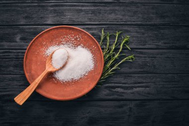 Bir plaka üzerinde bir tahta kaşık tuz. Ahşap bir arka plan üzerinde. Üstten Görünüm. Metin için boş alan.