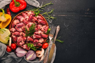 Çiğ tavuk kupa rosemary ile yemek pişirmek için hazır plaka üzerinde ve üzerinde baharat siyah ahşap arka plan. Üstten Görünüm. Metin için boş alan.