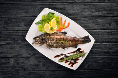 Balık alabalık pişmiş sebze ve baharatlar ile. Ahşap bir arka plan üzerinde. Üstten Görünüm. Metin için boş alan.