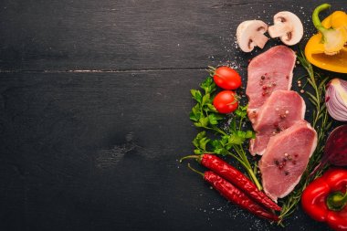 Taze sebze ve biberiye ve baharat siyah ahşap zemin sığır eti biftek. Üstten Görünüm. Metin için boş alan.