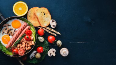 İngiliz kahvaltısı. Kızarmış yumurta, sosis, pastırma, fasulye, tost, domates, kahve fincanı taştan masada. Metin alanı olan Üstten Görünüm