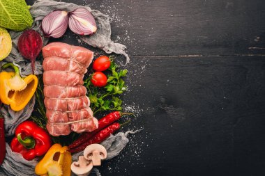 Taze sebze ve biberiye ve baharat siyah ahşap zemin ile çiğ et sığır filetosu. Üstten Görünüm. Metin için boş alan.