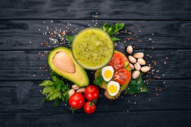 Avokado, yumurta, domates ve antep fıstığı ile sandviç. Kivi suyu. Ahşap bir arka plan üzerinde. Üstten Görünüm. Metniniz için boş alan.