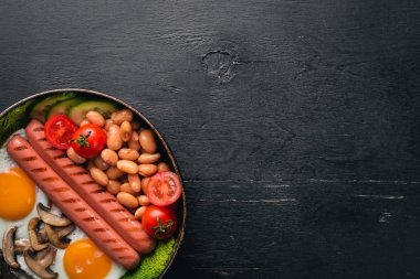 İngiliz kahvaltısı. Kızarmış yumurta, sosis, pastırma, fasulye, tost, domates, kahve fincanı taştan masada. Metin alanı olan Üstten Görünüm