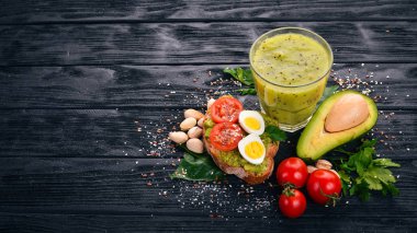 Avokado, yumurta, domates ve antep fıstığı ile sandviç. Kivi suyu. Ahşap bir arka plan üzerinde. Üstten Görünüm. Metniniz için boş alan.