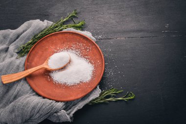 Bir plaka üzerinde bir tahta kaşık tuz. Ahşap bir arka plan üzerinde. Üstten Görünüm. Metin için boş alan.