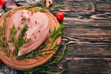 Biberiye ve baharat siyah ahşap zemin ile çiğ tavuk göğsü fileto. Üstten Görünüm. Metin için boş alan.