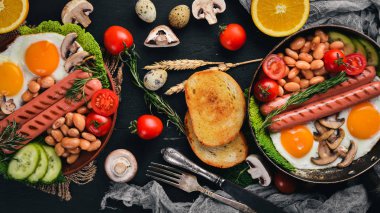 İngiliz kahvaltısı. Kızarmış yumurta, sosis, pastırma, fasulye, tost, domates, kahve fincanı taştan masada. Metin alanı olan Üstten Görünüm