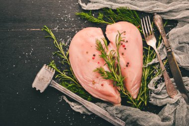 Biberiye ve baharat siyah ahşap zemin ile çiğ tavuk göğsü fileto. Üstten Görünüm. Metin için boş alan.