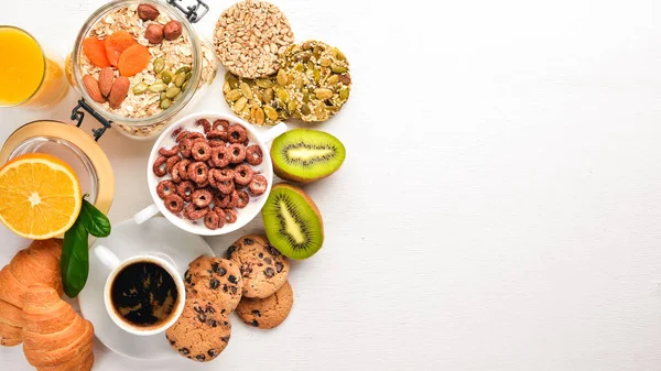 Fitness breakfast, muesli, milk, fruits, nuts and seeds, on a wooden surface. Top view. Free space for text.