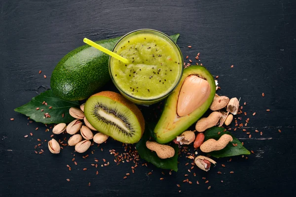 Kiwi smoothie and avocado with flaxseed and nuts. On a wooden background. Top view. Free space for your text.