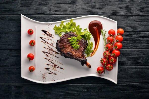 Steak on a bone with tomatoes and a hazelnut. Steak Fiorentino. On a wooden background. Free space for your text. Top view.