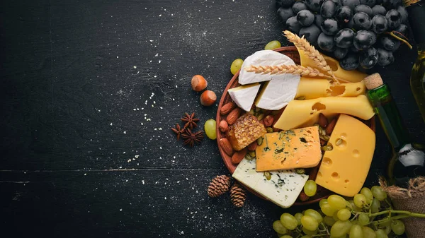 Assortment of cheeses, a bottle of wine, honey, nuts and spices, on a wooden table. Top view. Free space for text.