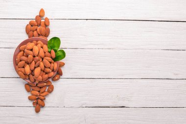 Badem fındık Beyaz ahşap zemin üzerinde. Sağlıklı aperatifler. Üstten Görünüm. Metin için boş alan.