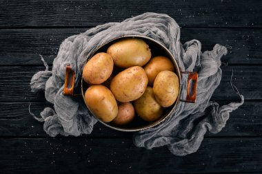 Çiğ patates siyah ahşap zemin. Yemek. Metin için özgür yer. Üstten Görünüm.