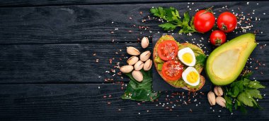 Bıldırcın yumurtası, avokado, domates ve antep fıstığı ile sandviç. Ahşap bir arka plan üzerinde. Üstten Görünüm. Metniniz için boş alan.