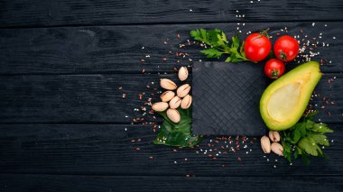 Yemek pişirmek için hazırlık. Avokado, Antep fıstığı, kiraz domates. Ahşap bir arka plan üzerinde. Üstten Görünüm. Metniniz için boş alan.