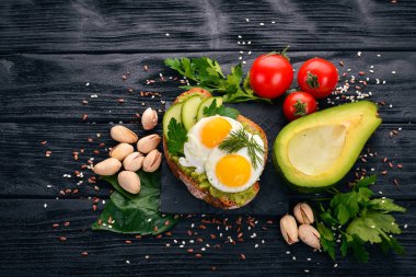 Bıldırcın yumurta, salatalık ve antep fıstığı ile avokado sandviç. Ahşap bir arka plan üzerinde. Üstten Görünüm. Metniniz için boş alan.