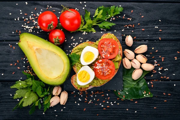 Bıldırcın yumurtası, avokado, domates ve antep fıstığı ile sandviç. Ahşap bir arka plan üzerinde. Üstten Görünüm. Metniniz için boş alan.