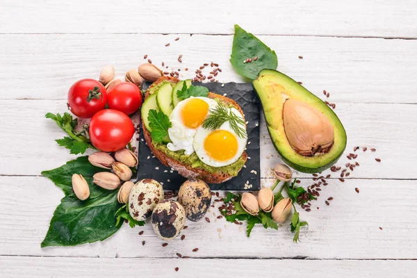 Bıldırcın yumurta, salatalık ve antep fıstığı ile avokado sandviç. Ahşap bir arka plan üzerinde. Üstten Görünüm. Metniniz için boş alan.