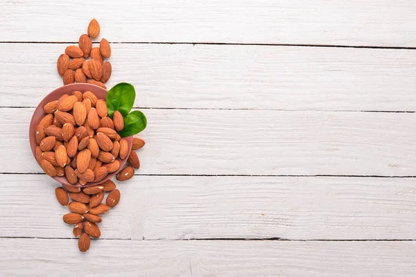 Badem fındık Beyaz ahşap zemin üzerinde. Sağlıklı aperatifler. Üstten Görünüm. Metin için boş alan.
