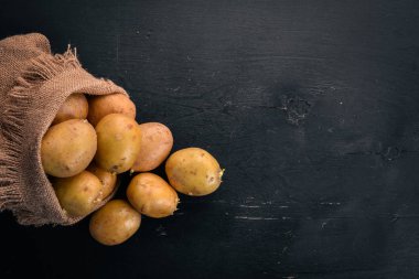 Çiğ patates siyah ahşap zemin. Yemek. Metin için özgür yer. Üstten Görünüm.