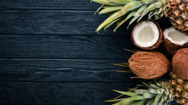 Hindistan cevizi ve ananas ahşap arka plan üzerinde. Tropikal meyve ve fındık. Üstten Görünüm. Metin için boş alan.