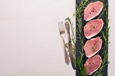 Çiğ et. Sığır eti biftek biberiye ve baharat beyaz ahşap zemin üzerinde. Üstten Görünüm. Metin için boş alan.