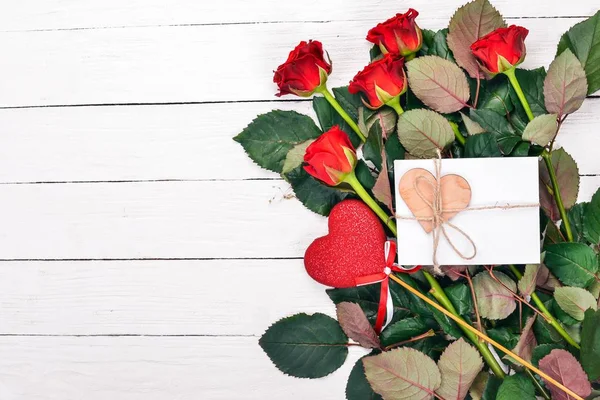 A letter for a loved one. An envelope, a rose, a gift. On a wooden background. Top view. Free space for your text.