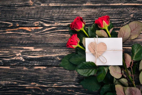 A letter for a loved one. An envelope, a rose, a gift. On a wooden background. Top view. Free space for your text.