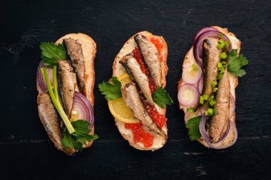 Hamsi ve havyar, soğan ve maydanoz, ahşap arka plan üzerinde sandviç kümesi. Üstten Görünüm. Kopya alanı.