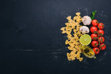 Ahşap arka plan üzerinde sebzeli makarna Farfalle kuru. Üstten Görünüm. Kopya alanı.